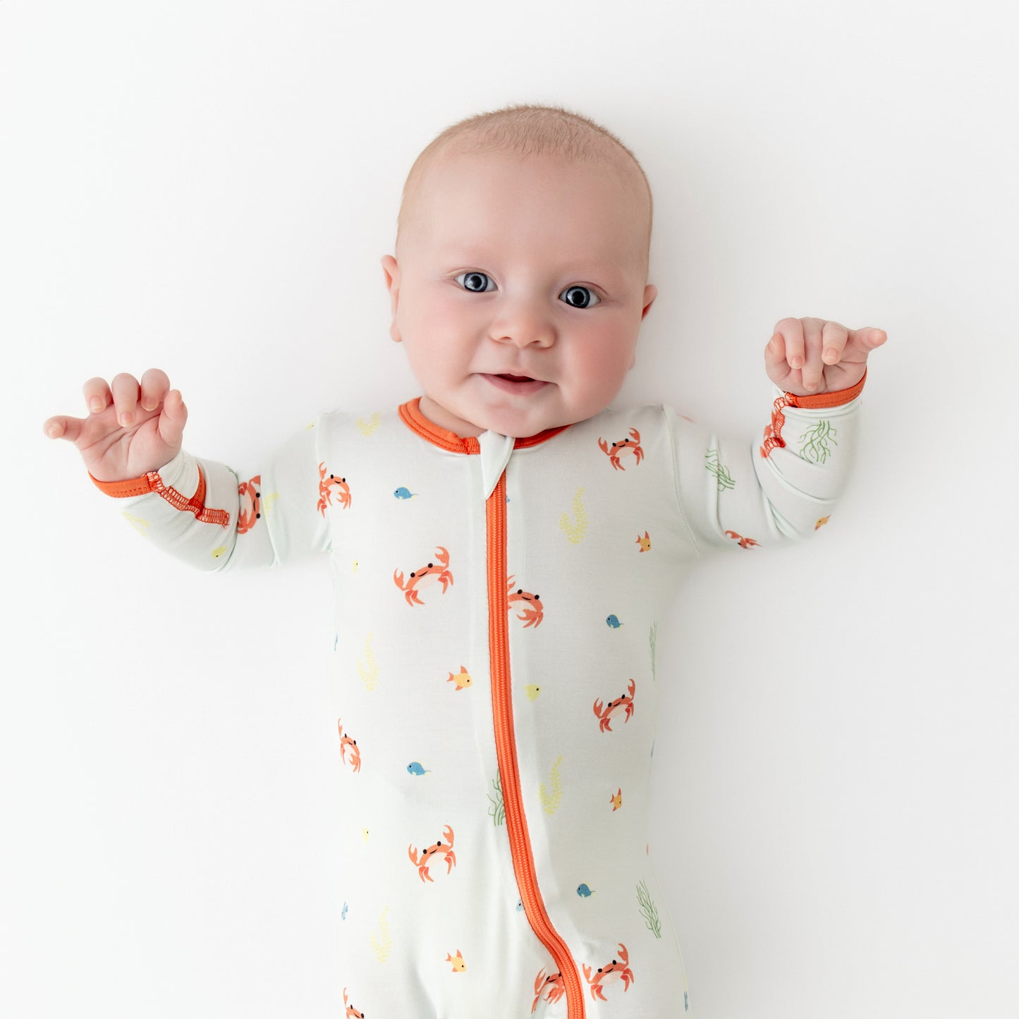 Baby wearing a footie made from bamboo viscose with a crab print
