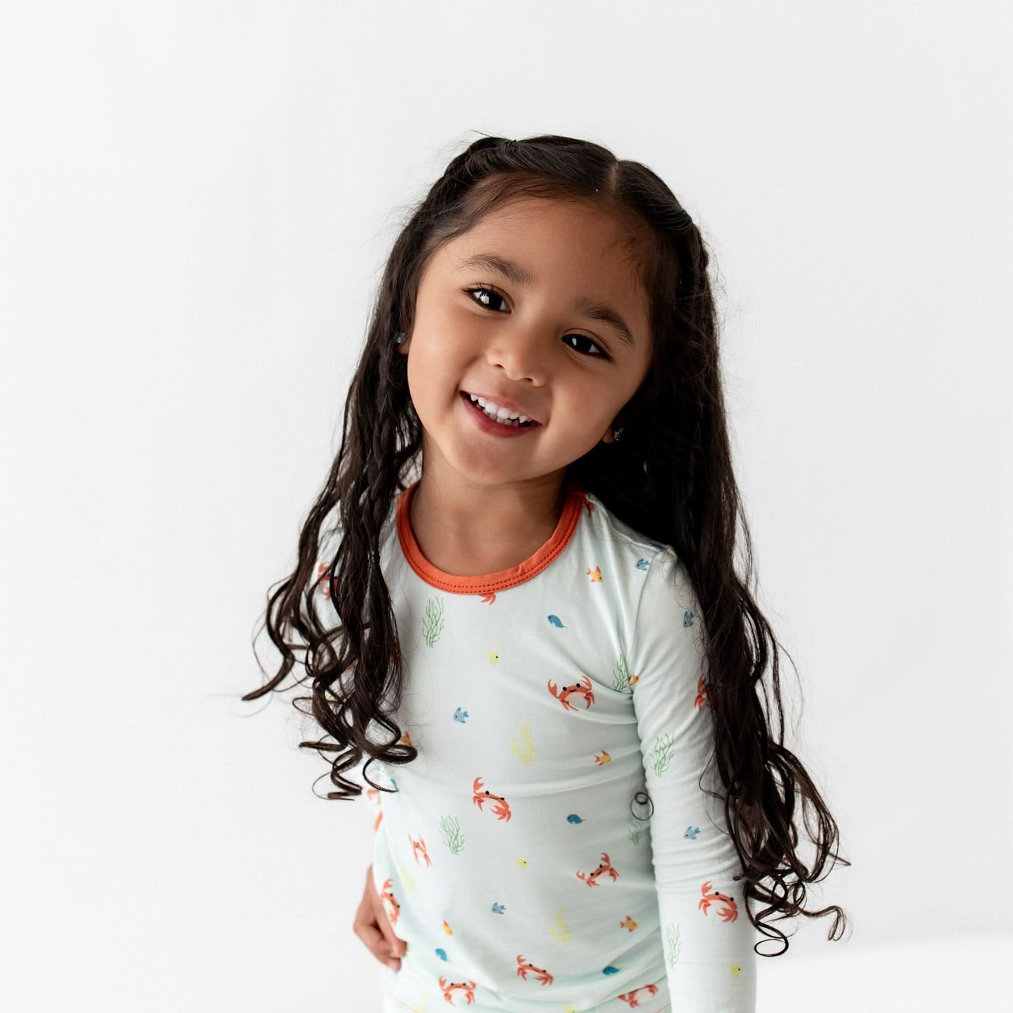 Smiling toddler wearing crab print bamboo pajamas, playing happily