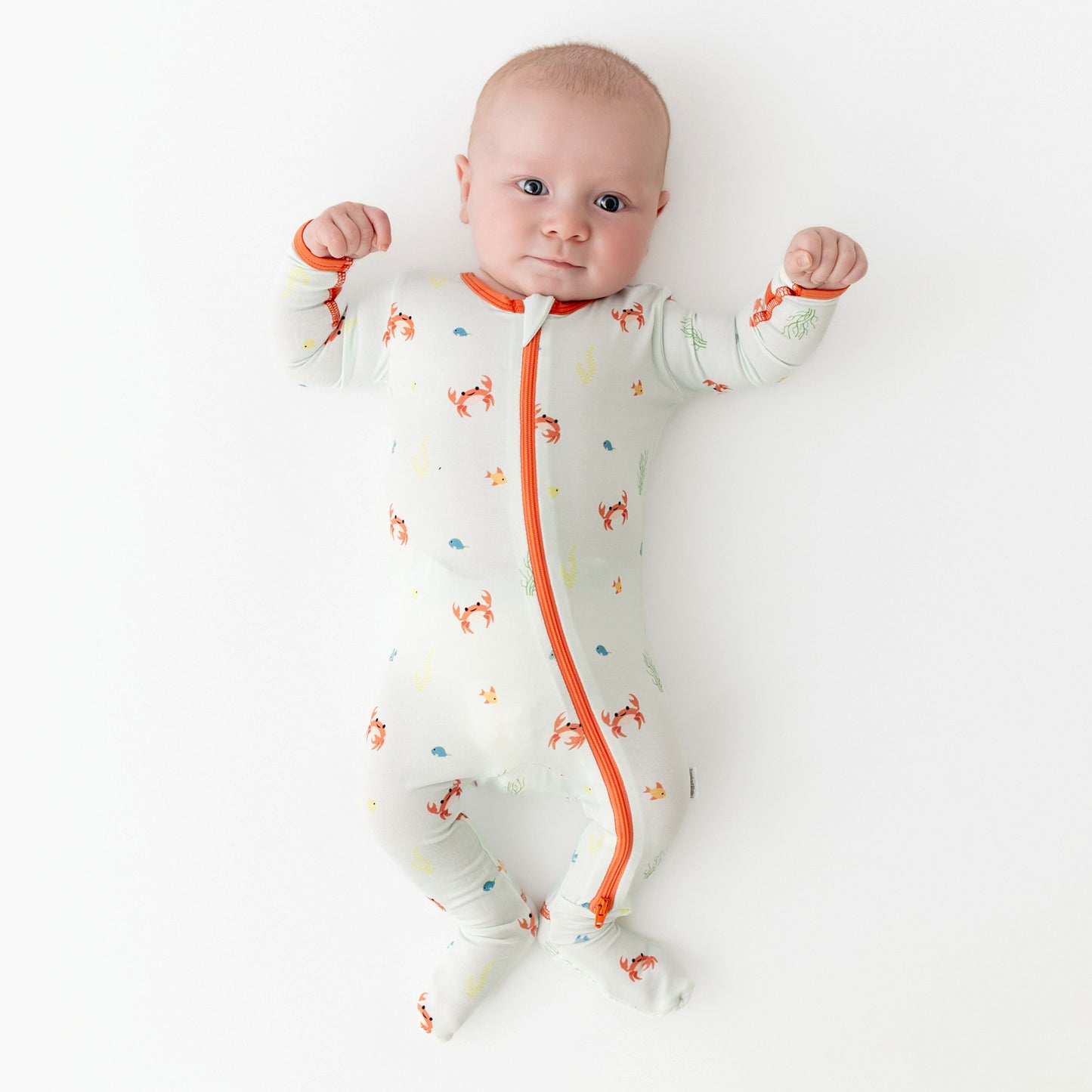 Baby wearing bamboo footie with crab print, front view