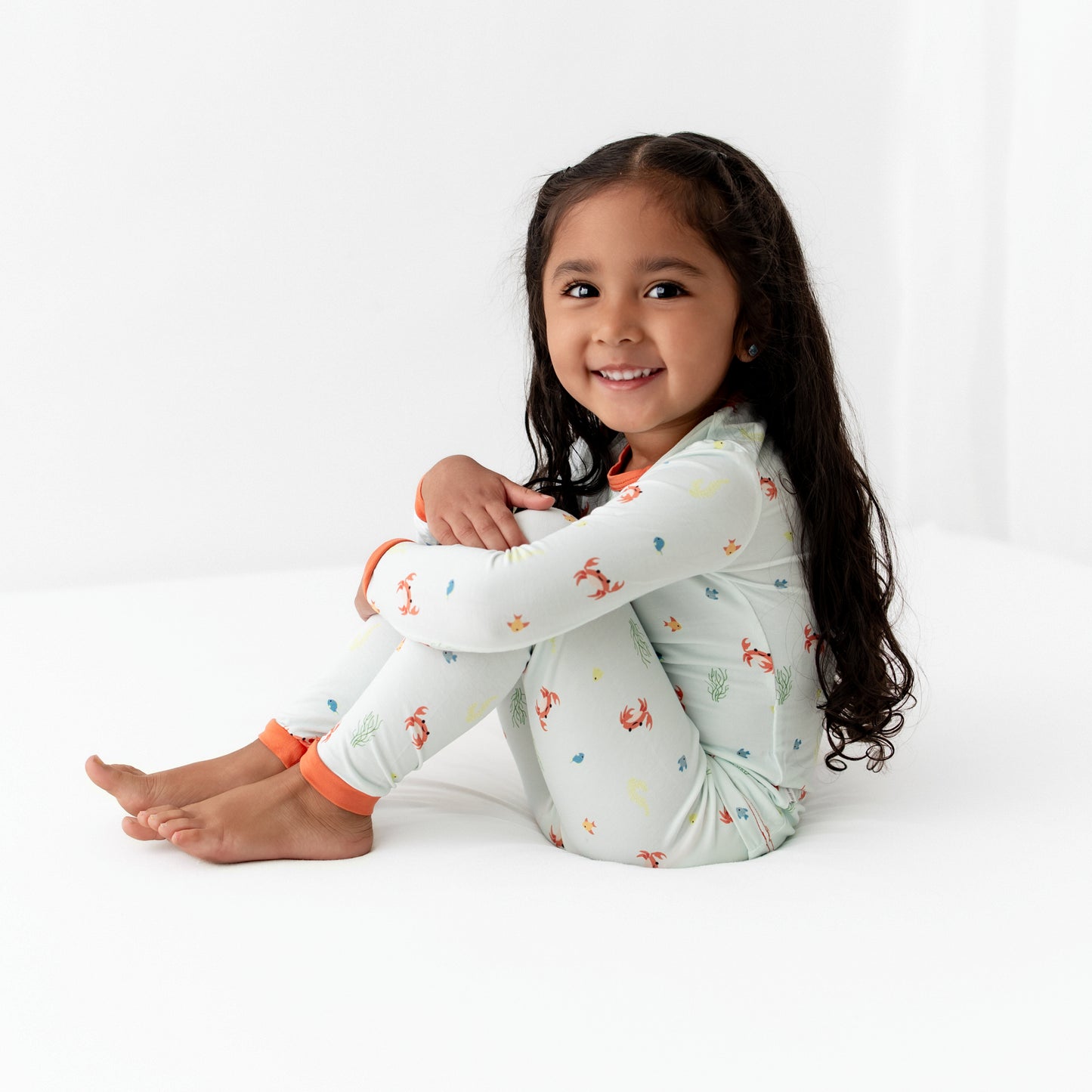 Smiling toddler wearing crab print bamboo pajamas, playing happily