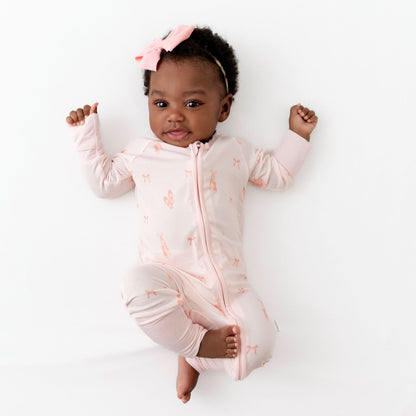 Baby wearing a pink romper with a ballerina print