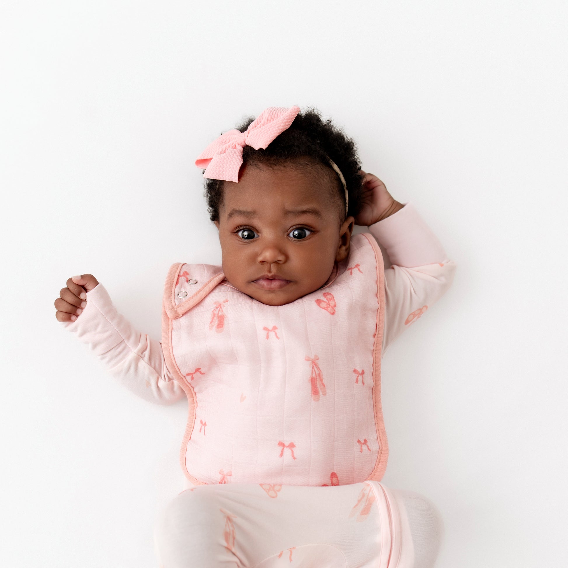 Baby wearing a pink ballerina outfit with matching ballerina bib